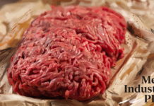 Flowpack для крупноформатного мясного фарша без пластикового лотка Крупноформатный мясной фарш в упаковке flowpack без пластикового лотка — прямоугольная порция сырого фарша розово-красного цвета герметично упакована в прозрачную гибкую плёнку; продукт лежит на светлом фоне с выразительными живописными мазками бежевых, кремовых и коричневых оттенков, в правом нижнем углу размещён логотип Meat Industry PRO.